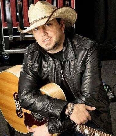 a man with a cowboy hat sitting in front of a guitar