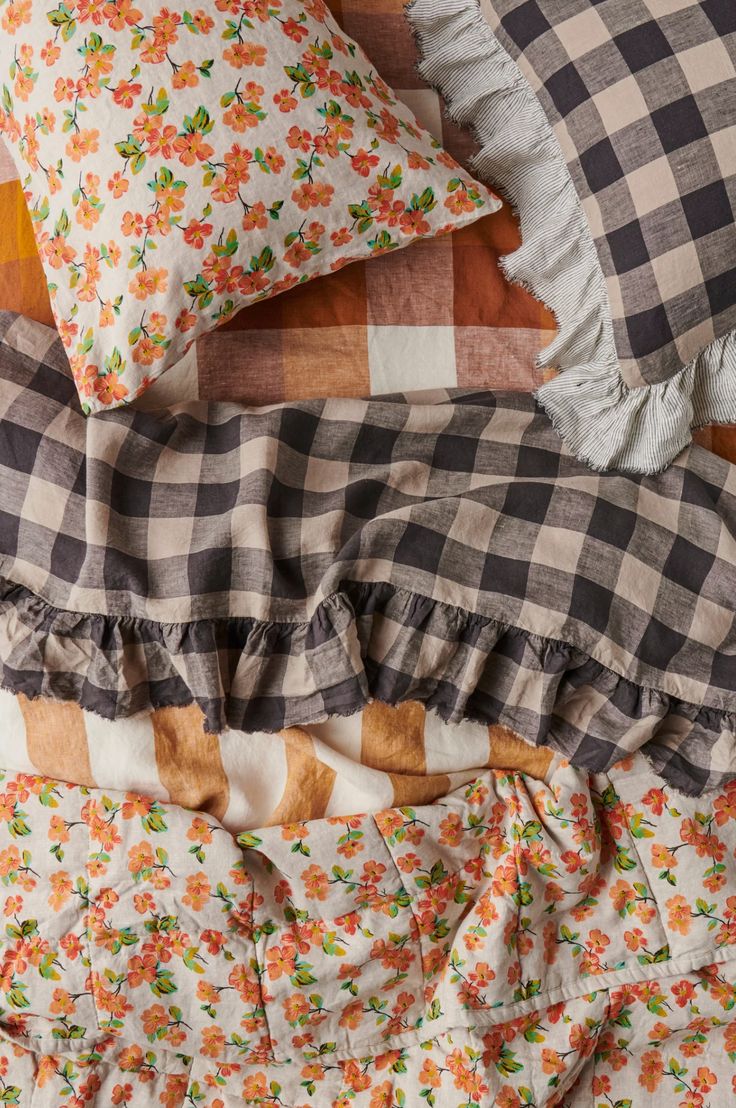 the bed is made up with many different pillows and blankets on top of each other