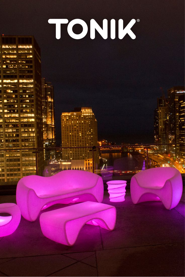 there is a pink couch and chair on the top of a building with lights in front of it