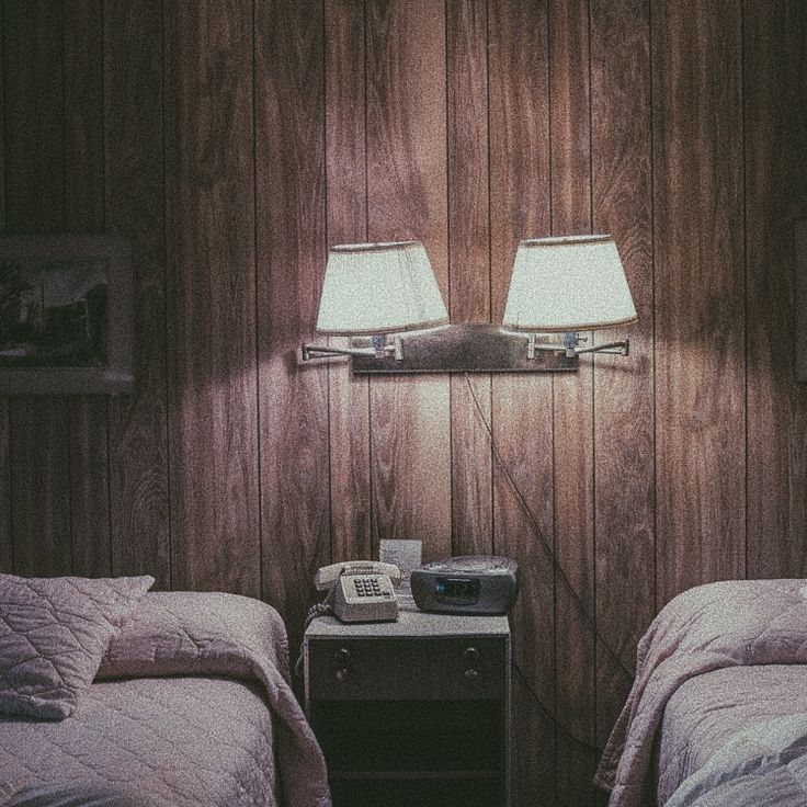 two twin beds in a room with wood paneling on the walls and lamps on the nightstands