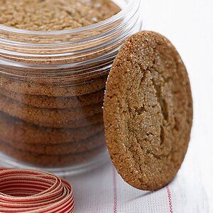 a cookie in a glass jar next to a red and white striped ribbon