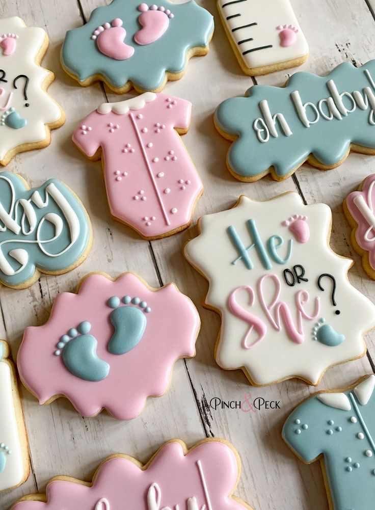 baby shower cookies decorated with blue, pink and white icing on a wooden table