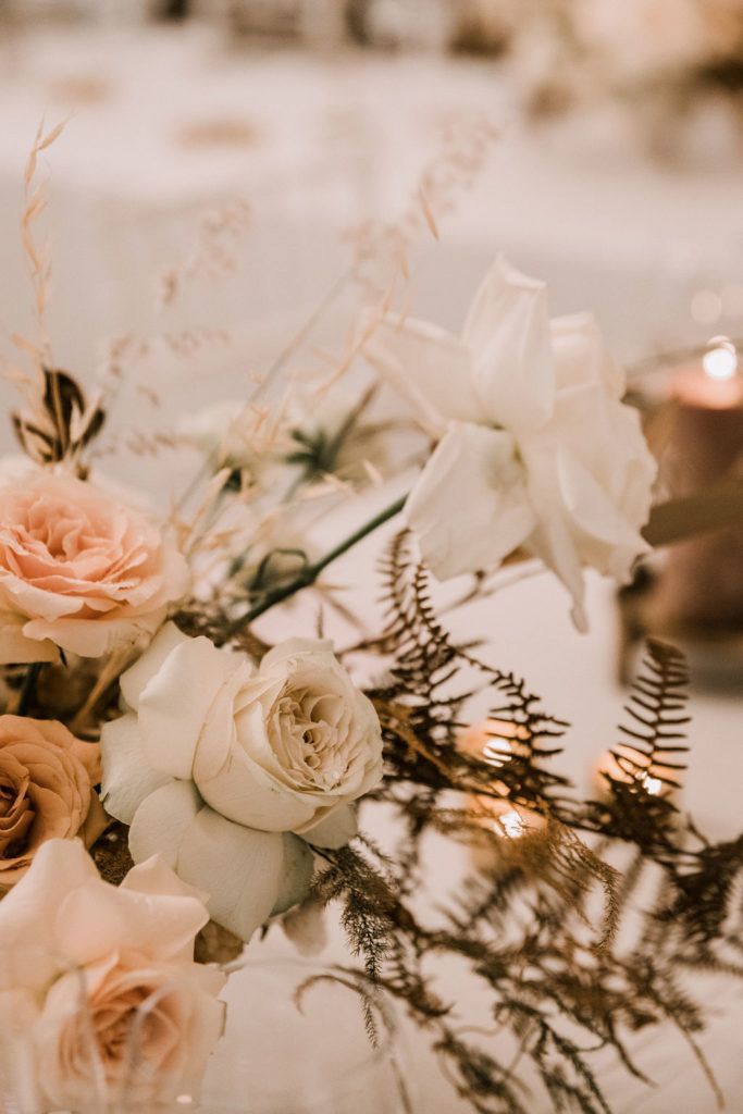 a vase filled with white and pink flowers on top of a table next to candles