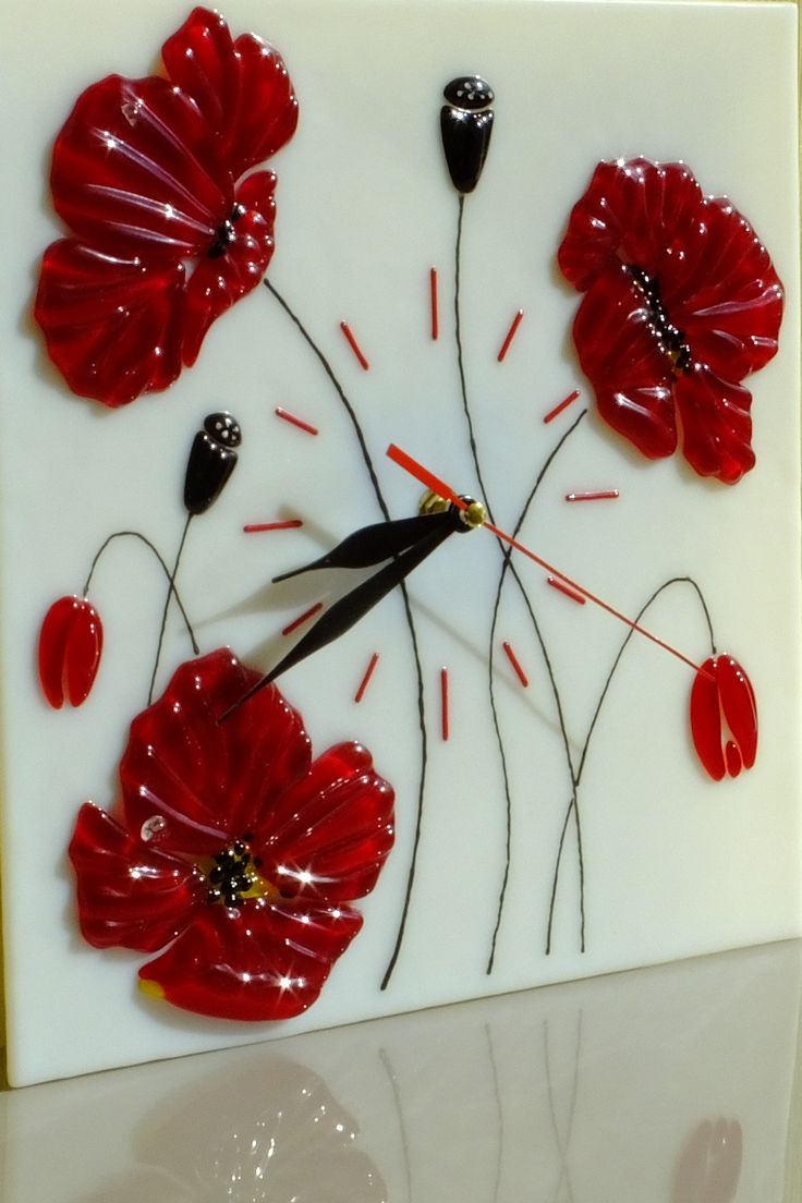 a glass clock with red flowers on it