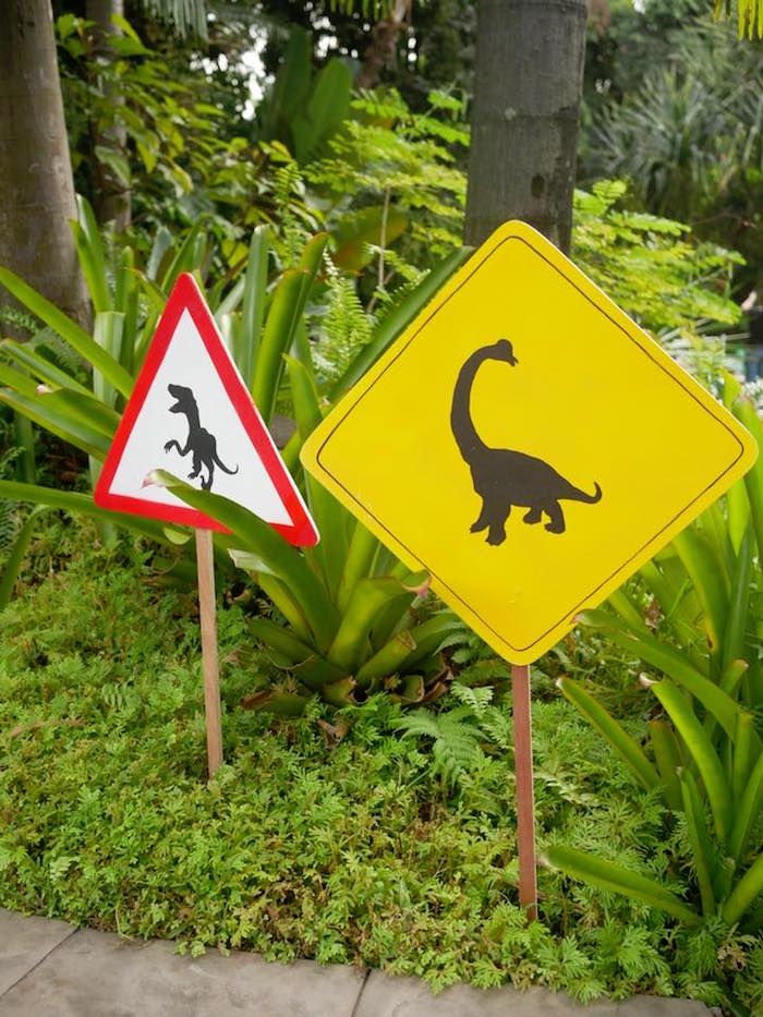 two street signs that are next to each other in the grass with trees and bushes behind them