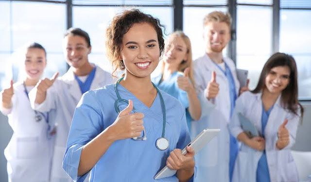 a group of doctors giving thumbs up in front of the camera with one woman holding a clipboard