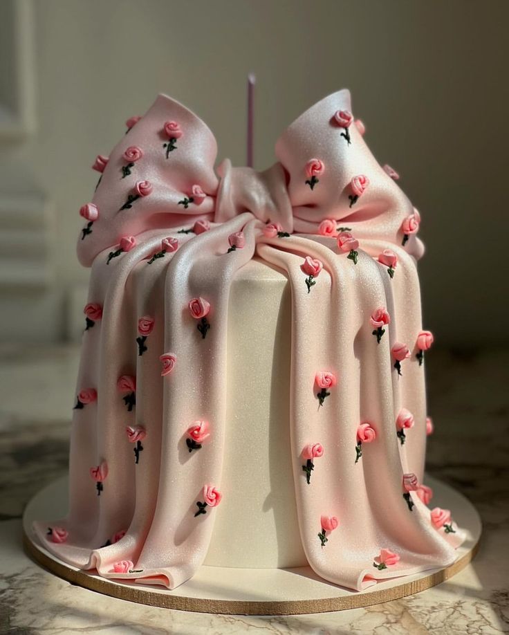 a white cake with pink flowers on it and a candle sticking out of the top