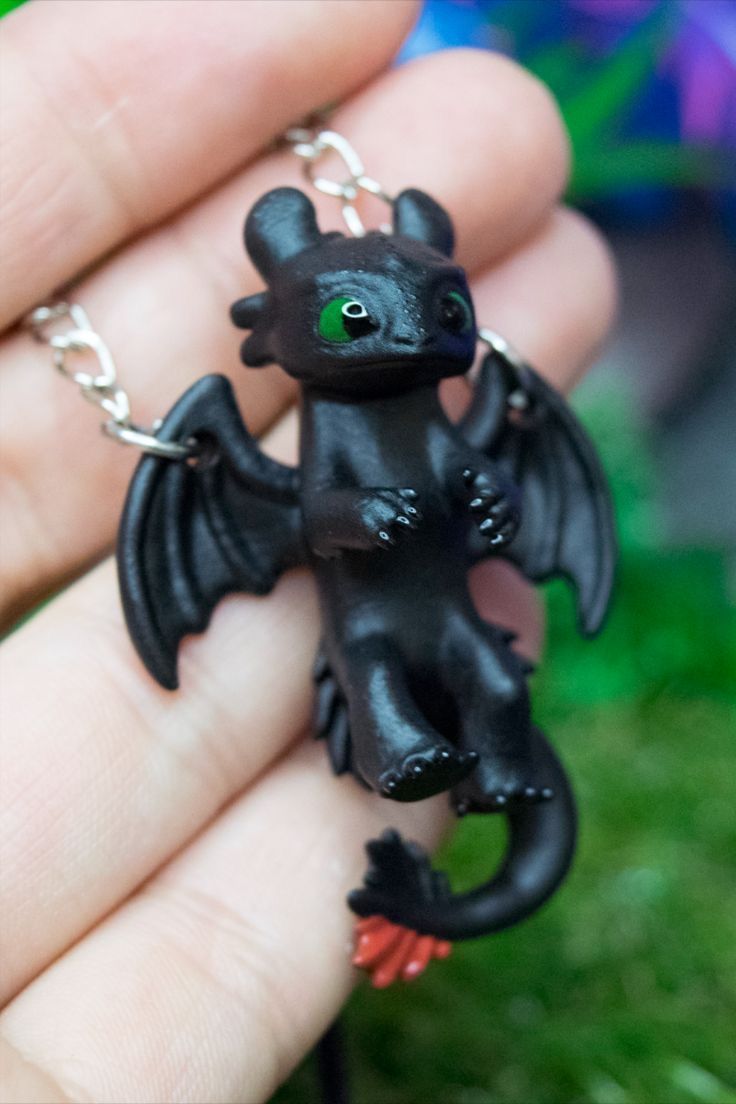 a small black dragon figurine being held in someone's hand