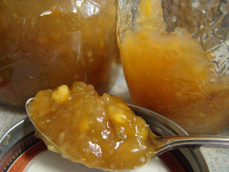 a spoon with some food on it next to two jars filled with jelly and orange juice