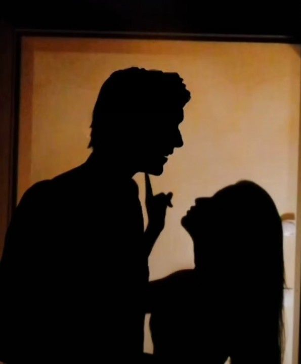 a man and woman are silhouetted against a wall with the shadow of their face