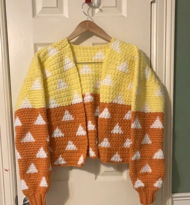 an orange and yellow sweater hanging on a door