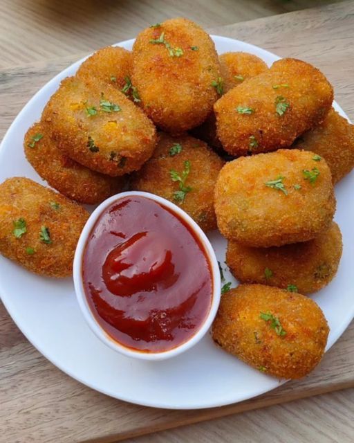 some fried food on a white plate with ketchup and dipping sauce in the middle