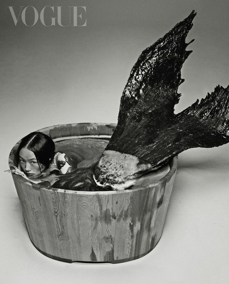 black and white photograph of woman in wooden bowl with bird