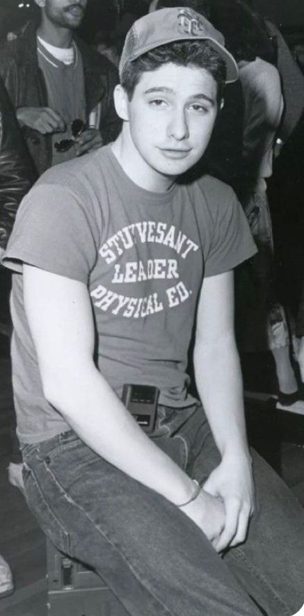 black and white photograph of young man sitting in front of other people wearing baseball caps