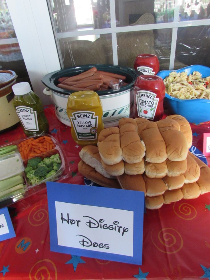 a table topped with lots of food and condiments next to a sign that says hot disney does