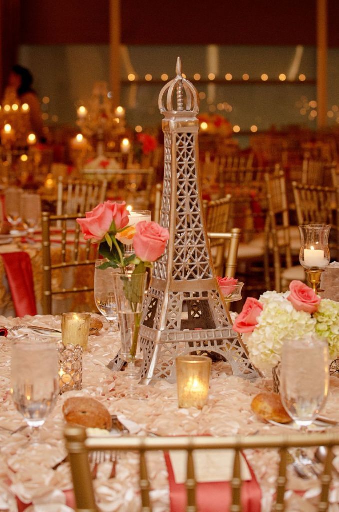 the eiffel tower centerpiece is surrounded by candles, flowers and vases