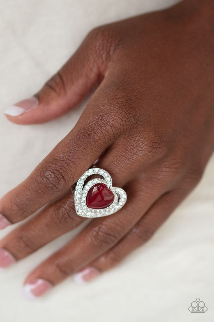 Chiseled into a charming heart shape, a glowing red cat's eye stone is pressed into the center of two silver heart frames radiating with glassy white rhinestones, creating a romantic centerpiece atop the finger. Features a stretchy band for a flexible fit. Sold as one individual ring. P4RE-RDXX-126XX Paparazzi Rings, What The Heart Wants, Heart Wedding Rings Sets, Romantic Centerpieces, Bling Party, Paparazzi Accessories Jewelry, Red Ring, Dainty Band, Silver Heart Ring