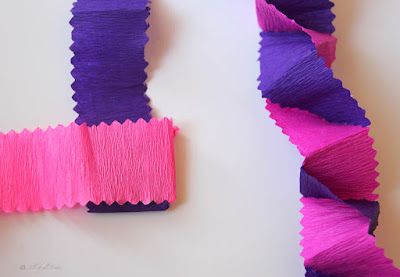 purple and pink strips of yarn on a white surface