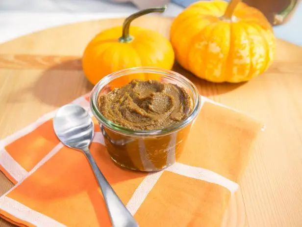 a small jar of peanut butter sits on a placemat with two pumpkins in the background