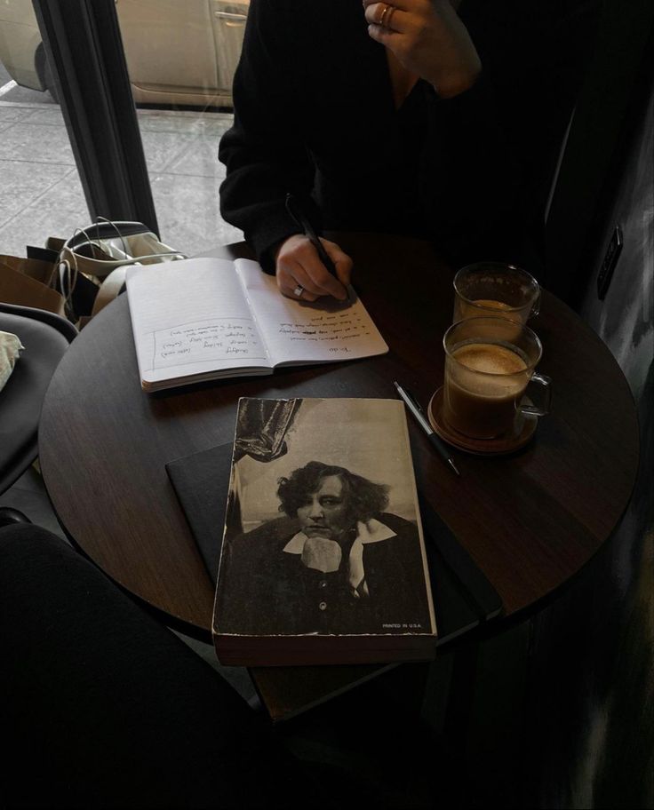 a person sitting at a table with an open book and coffee in front of them