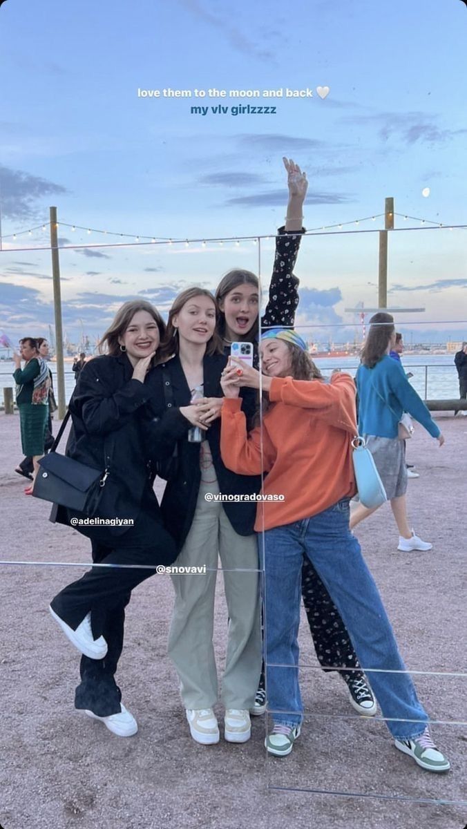 three girls posing for the camera with their arms in the air and one girl holding up her hand