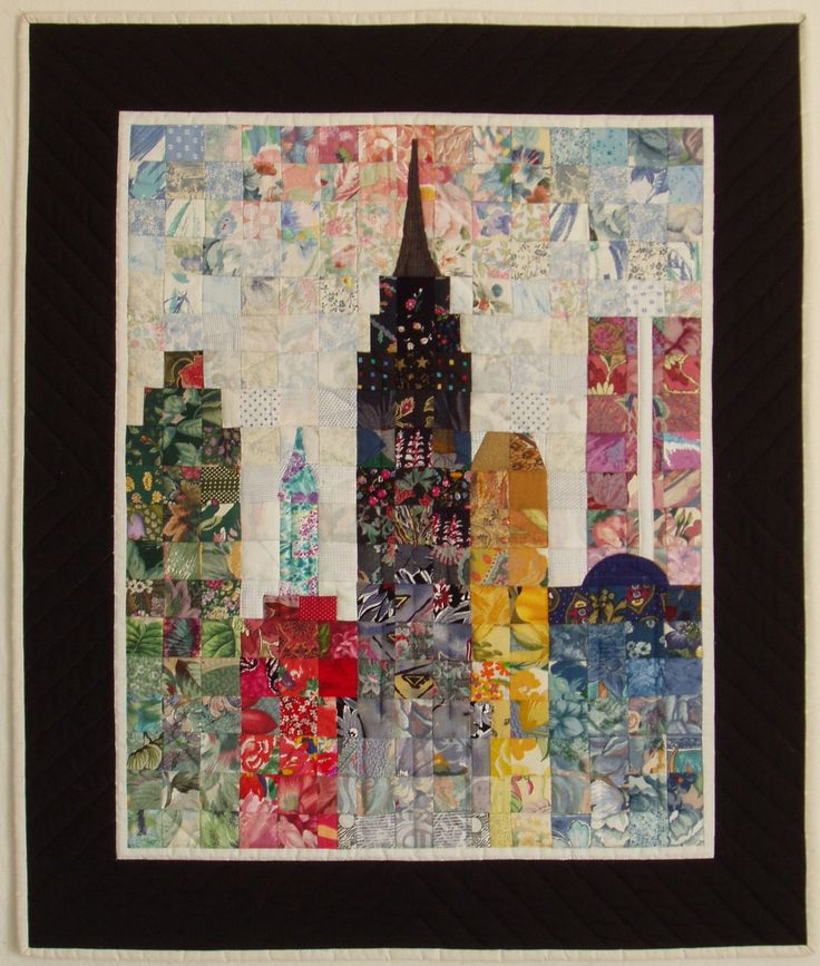 a quilted wall hanging with a city skyline in the center and lots of different colors