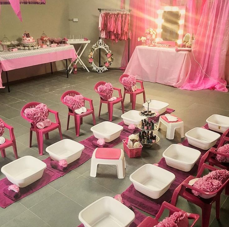 a room filled with pink and white chairs next to a table covered in cake on top of it