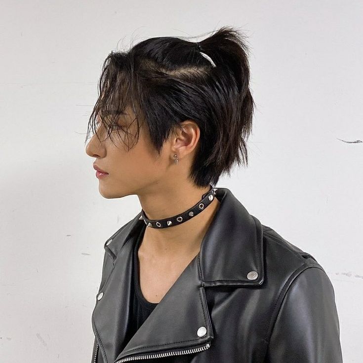 a woman with black hair wearing a leather jacket and choker necklace on her neck