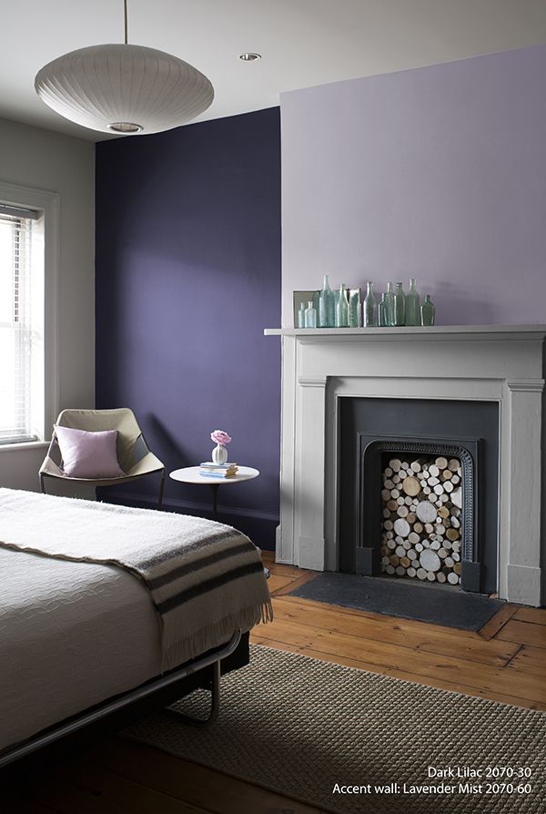 a bedroom with purple walls and a fireplace