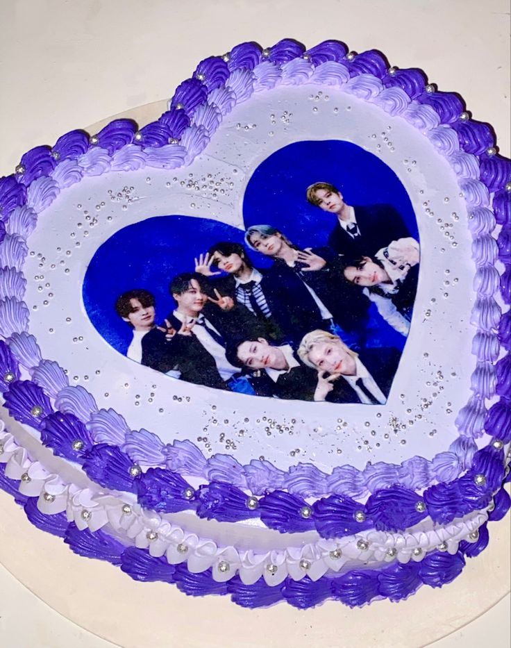 a heart shaped cake decorated with photos of two men in tuxedos on it