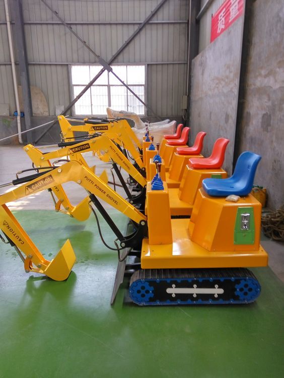 several different types of construction equipment sitting in a warehouse with green flooring and walls