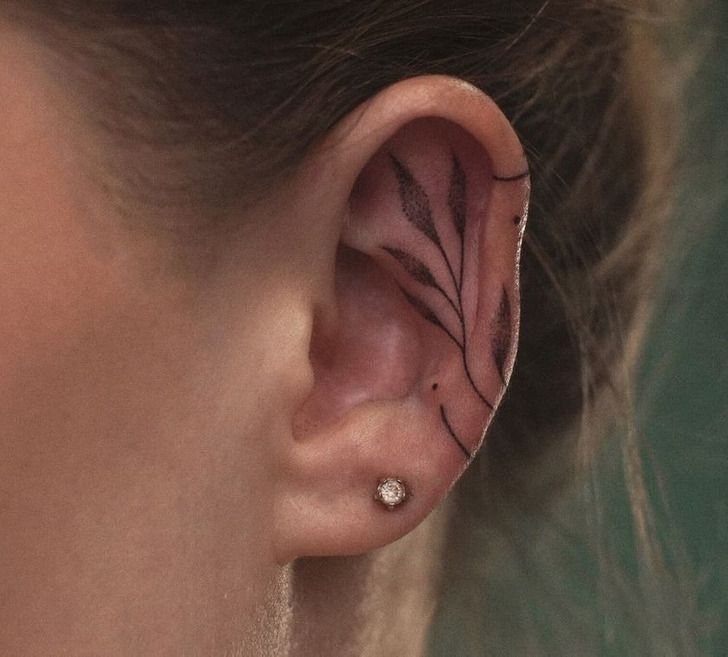 a woman's ear with an artistic design on the middle part of her ear