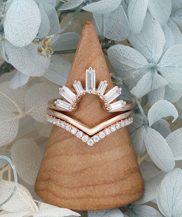 a diamond ring sitting on top of a piece of wood next to leaves and flowers