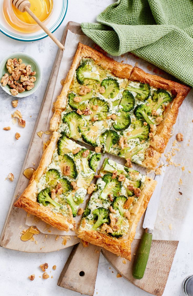 cucumber and cheese tart on a cutting board next to a bowl of nuts