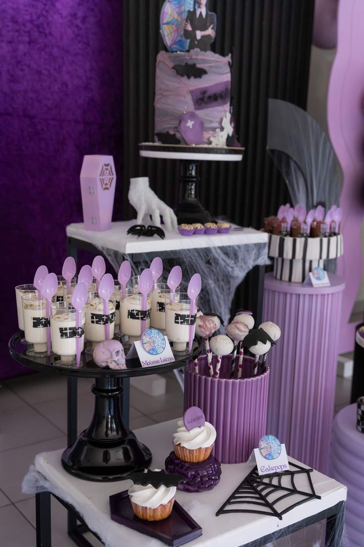 a table topped with cupcakes and cakes covered in purple frosting on top of it