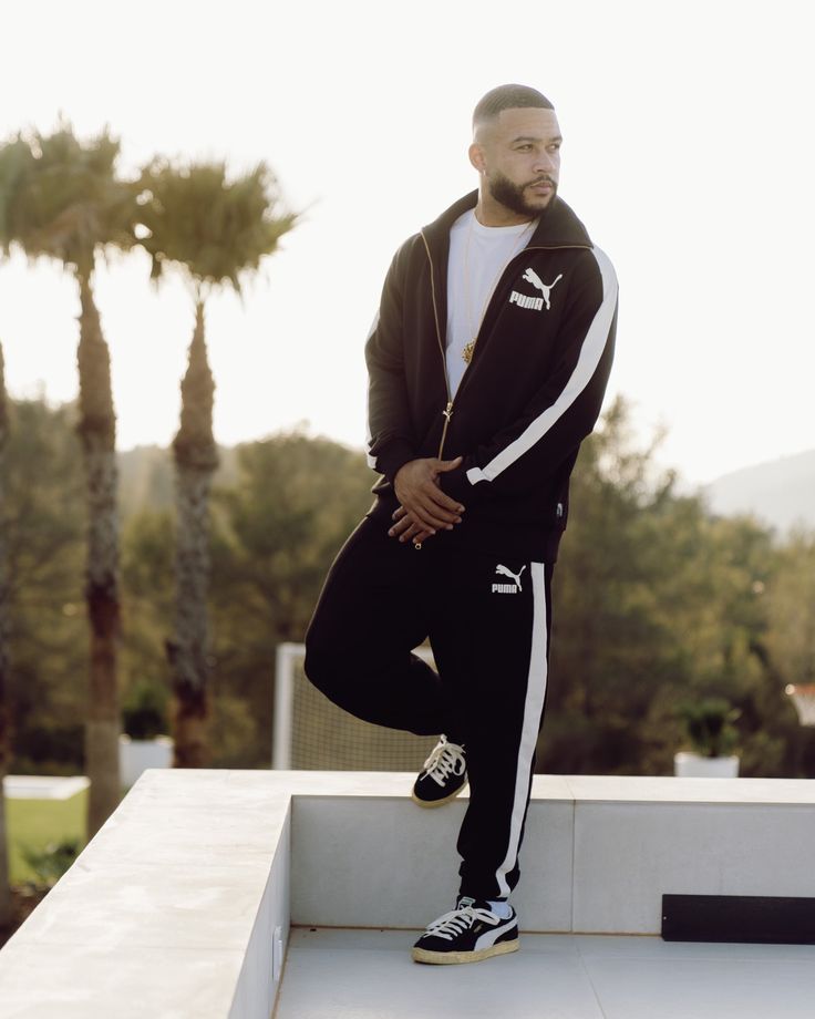 a man standing on top of a white wall next to palm trees in the background