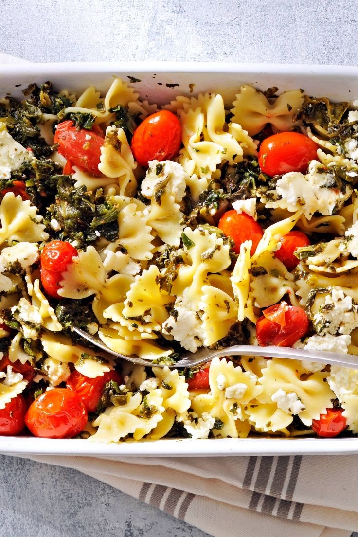 a casserole dish with tomatoes, spinach and feta cheese