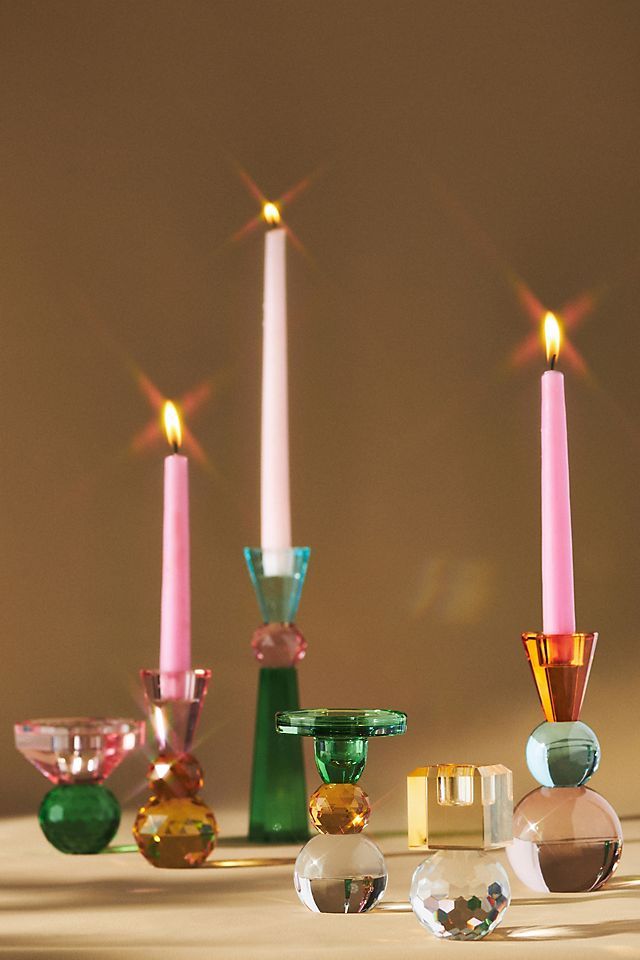 three candles are sitting next to each other with different colored glass objects in front of them