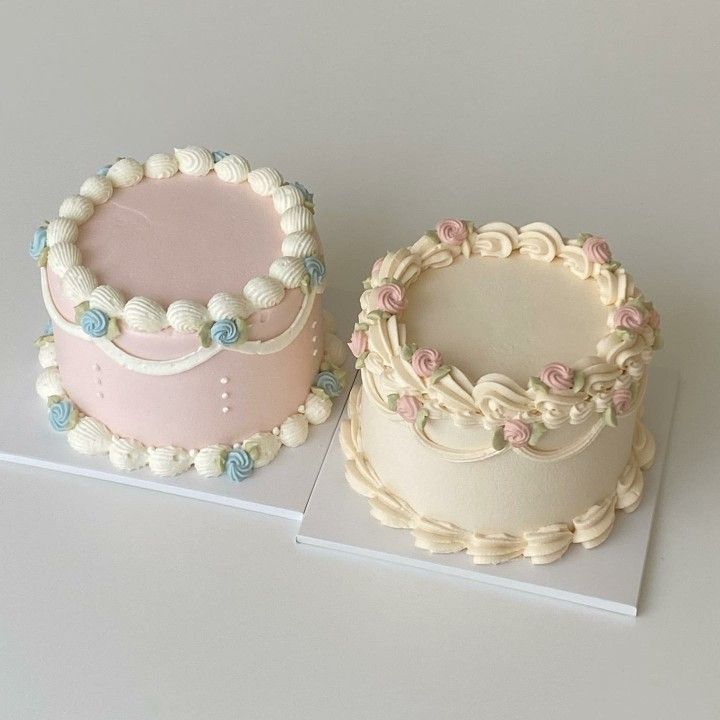 two cakes sitting side by side on top of a white table with pink and blue frosting