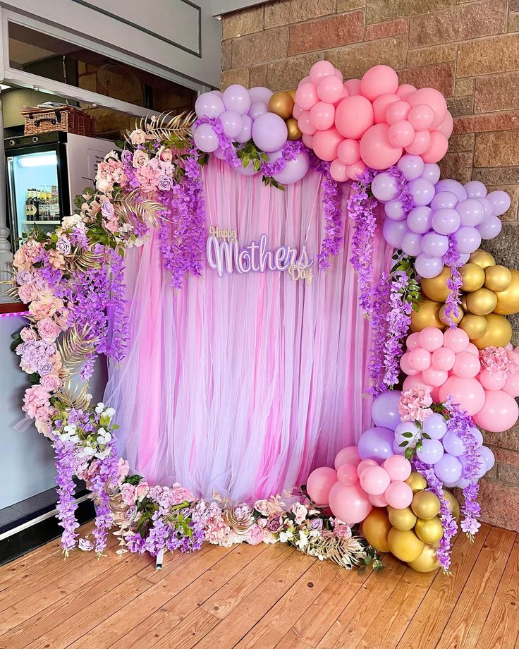 a pink and purple backdrop with flowers, balloons and the word mother written on it