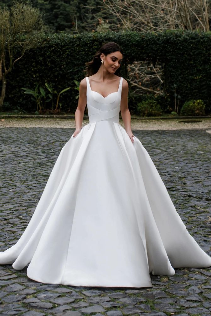 a woman in a white wedding dress standing on cobblestone