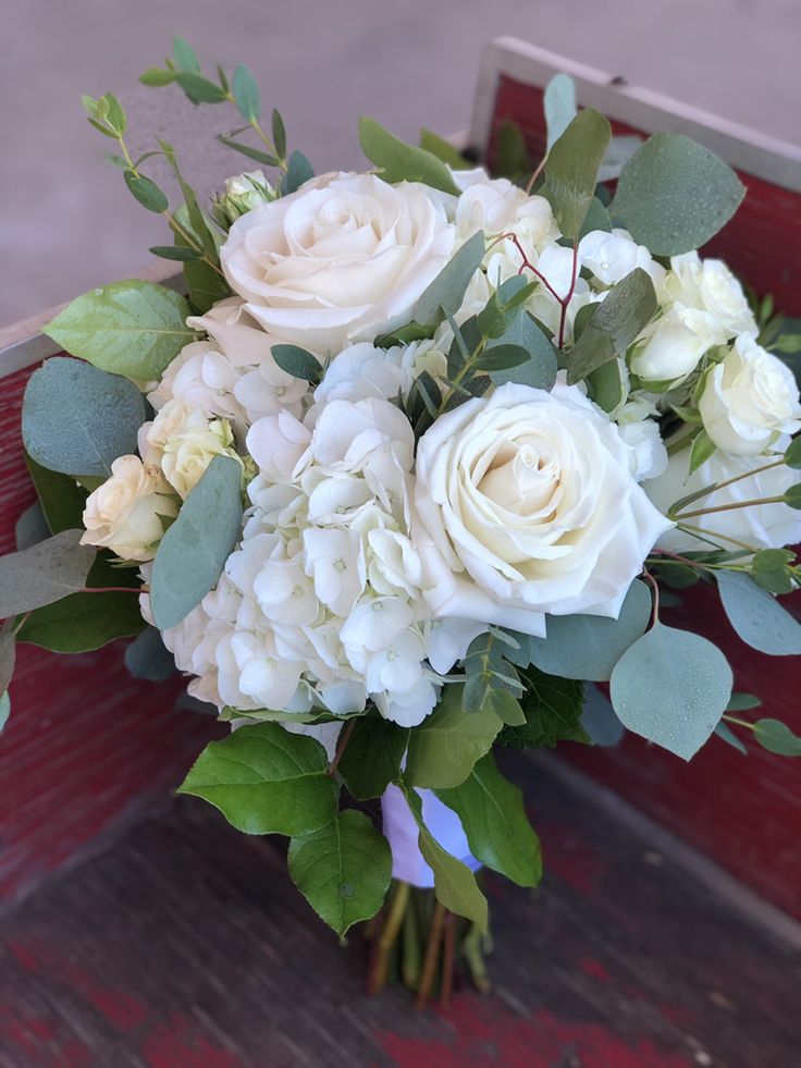 a bouquet of white flowers sitting on top of a wooden bench