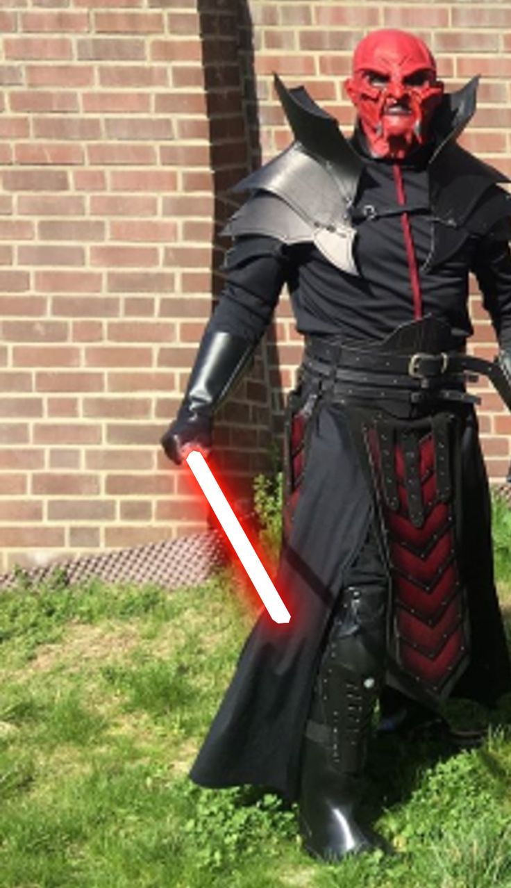 a man dressed up as darth vader in front of a brick wall and grass