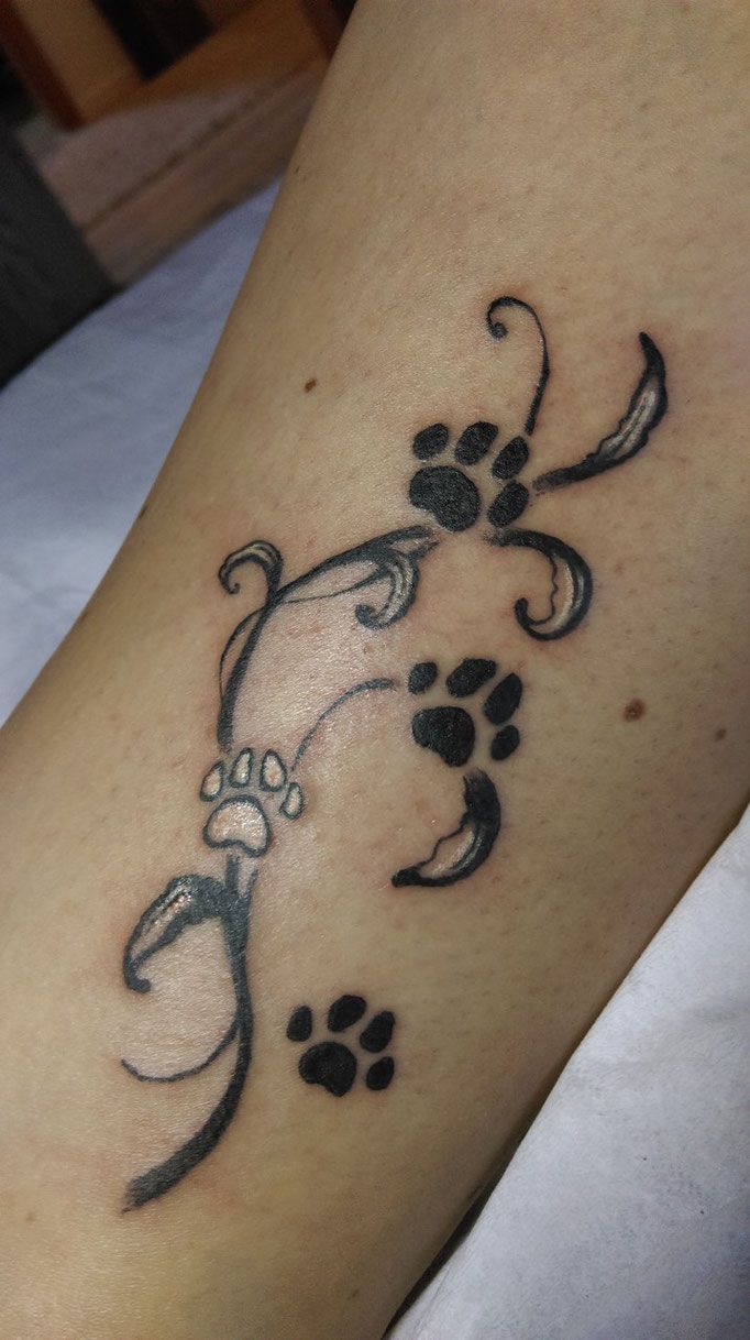 a tattoo on the leg of a woman that has paw prints and an ornament