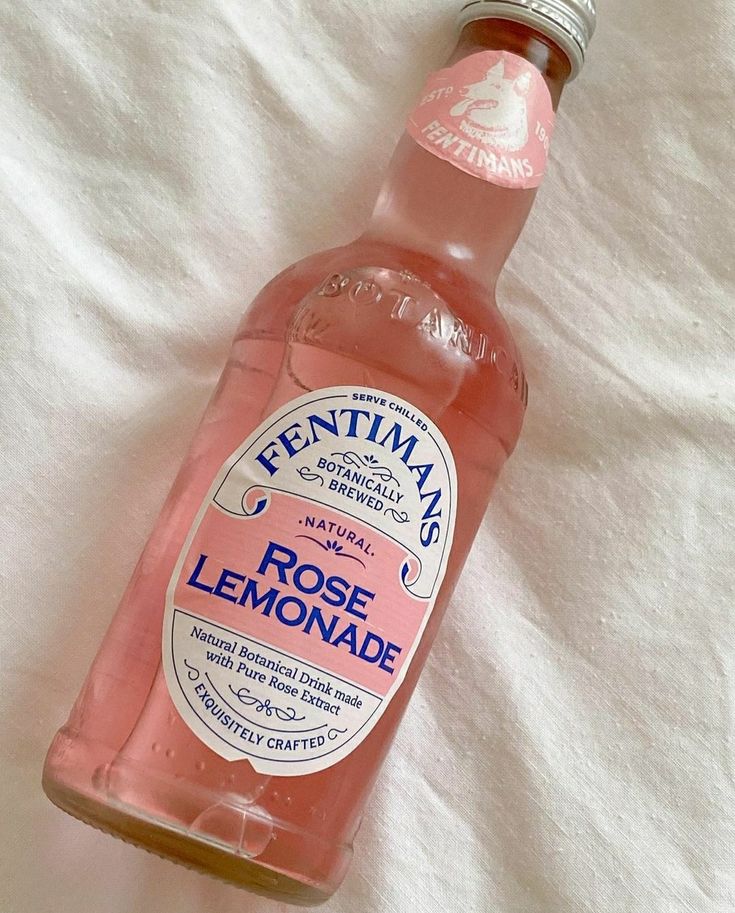 a bottle of pink lemonade sitting on top of a bed