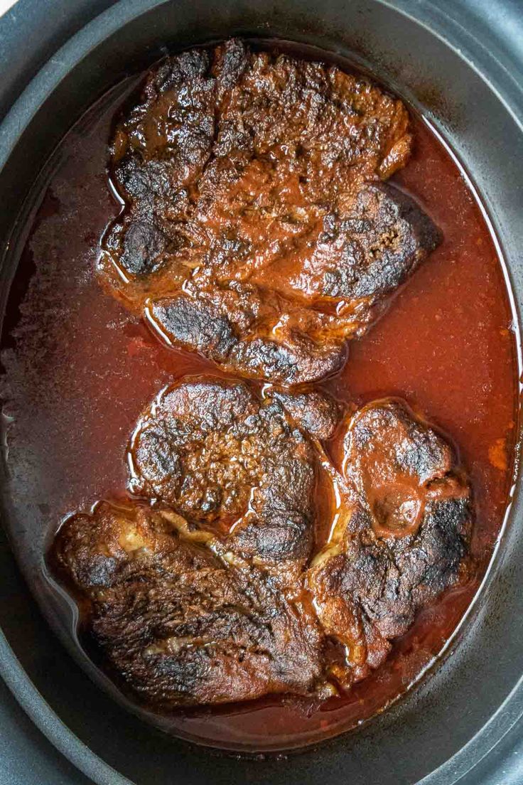 three pieces of meat in a pot with sauce