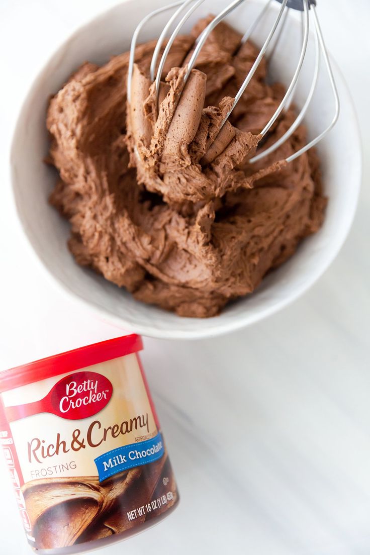 chocolate frosting in a white bowl with a whisk on the side next to it