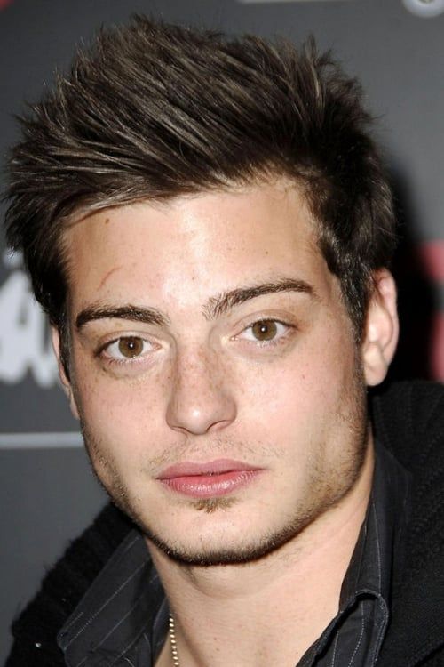 a close up of a person wearing a black shirt and jacket with a necklace on his neck