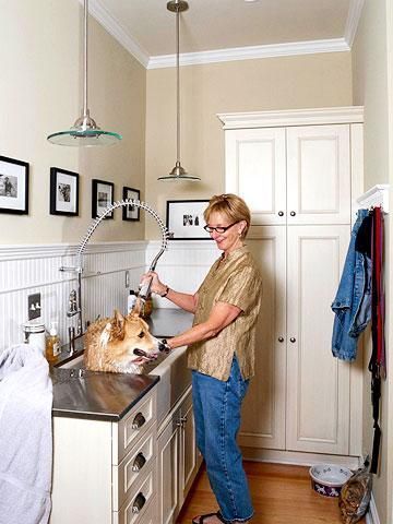 a woman washes her dog in the kitchen with a faucet and sink