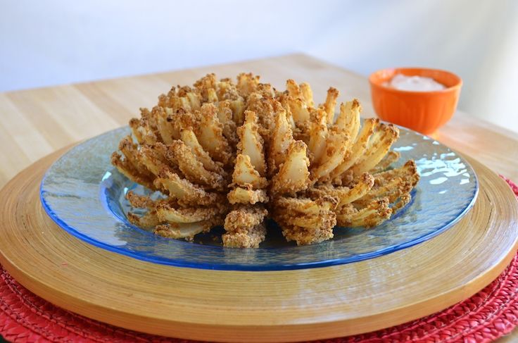 oven - fried onion bloom with tangy dipping sauce on a blue plate next to an orange bowl